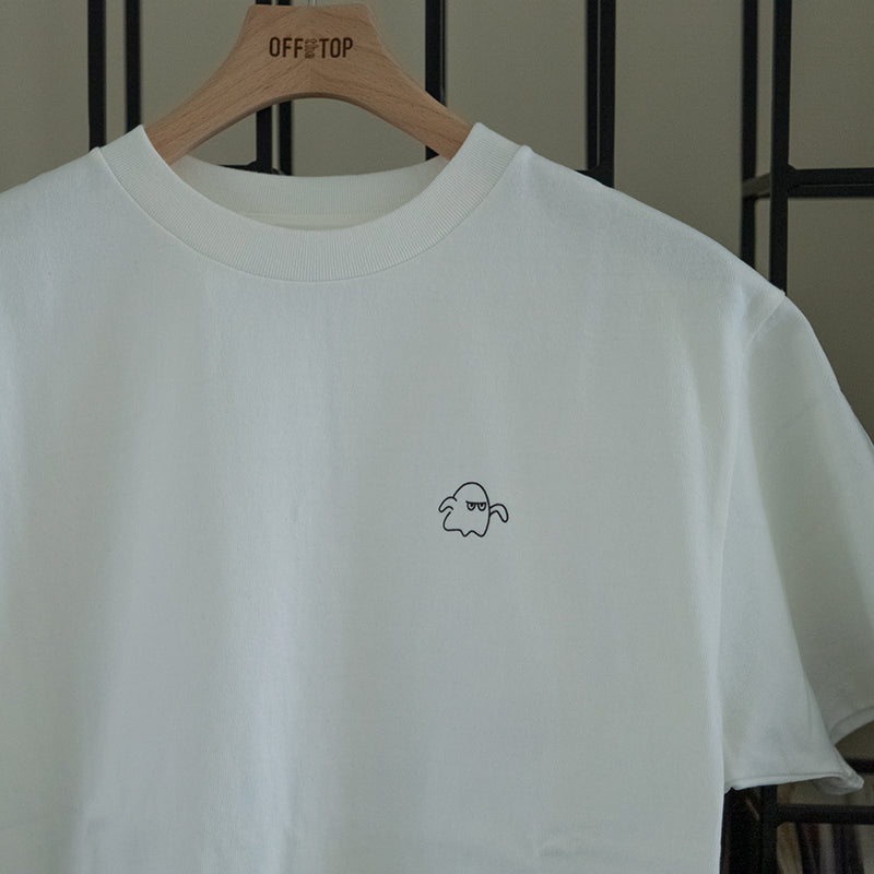 OFF the TOPの木製ハンガーに掛かったホワイトの半袖Tシャツ。左胸部分に、黒い線画で可愛いお化けのキャラクターがシルクスクリーンでプリントされています。